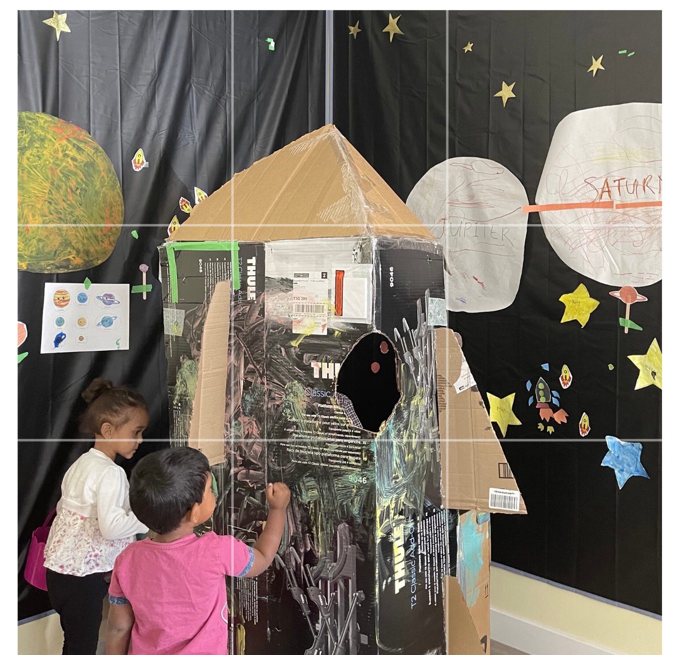 School-age children building a cardboard rocket for a space project