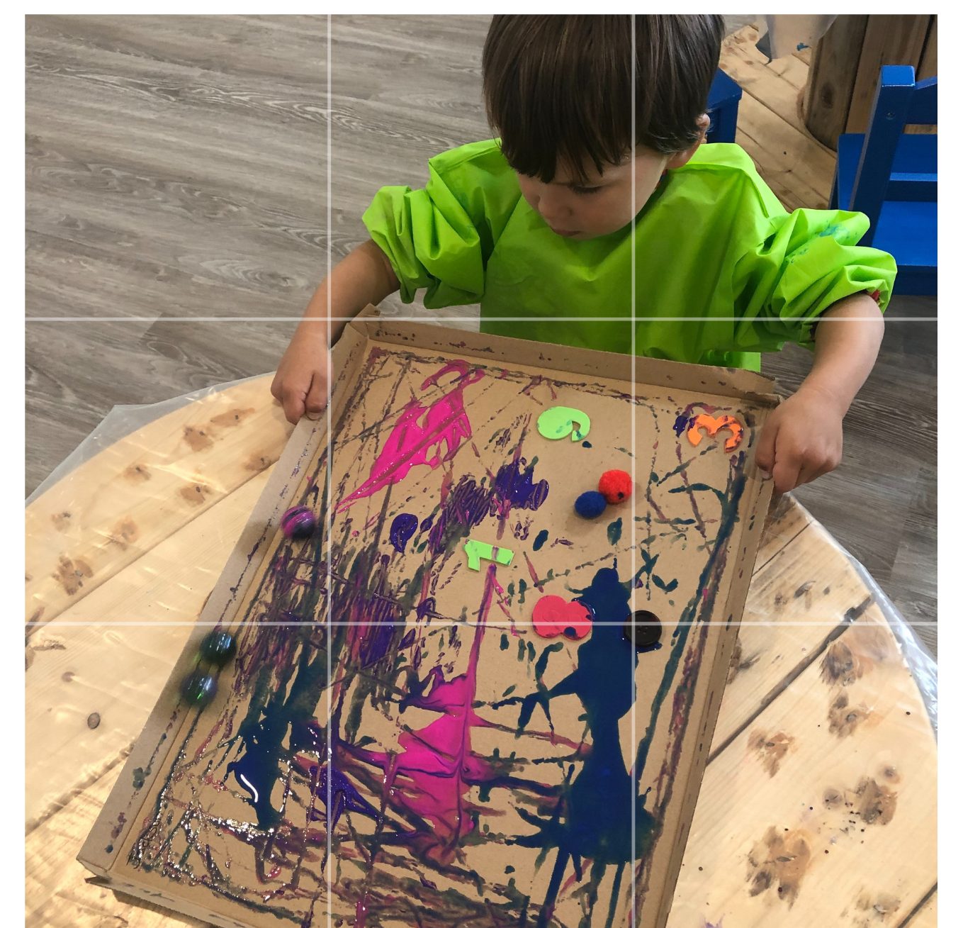 A child rolling marbles through paint to make patterns